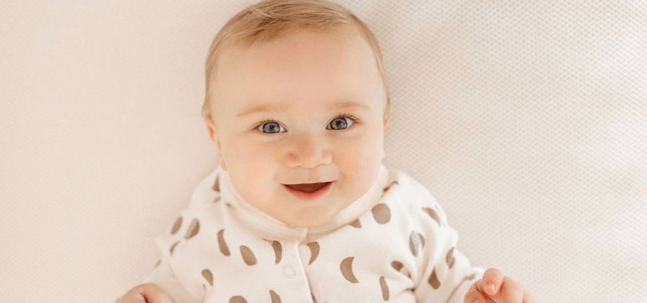Smiling baby on bare, breathable mattress