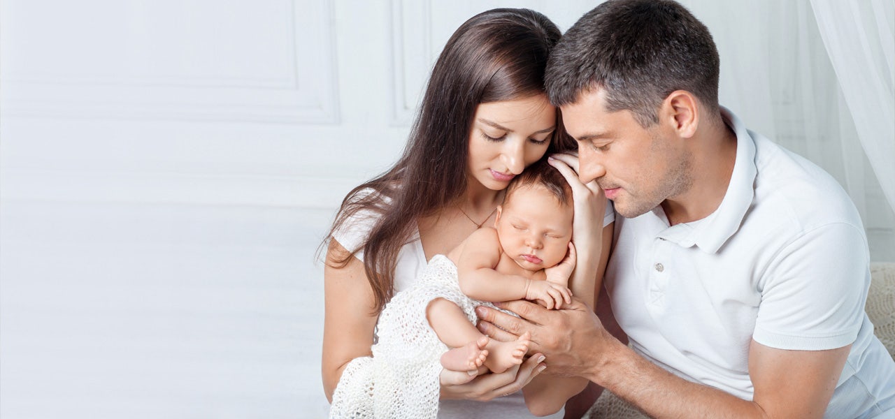 Profressional portrait of a mother, father and small infant snuggling 