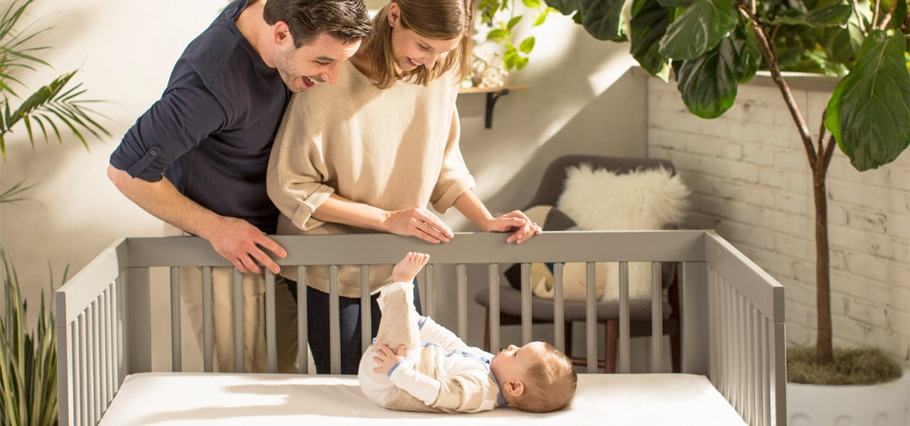 Parents smiling over the crib at a happy, awake baby 