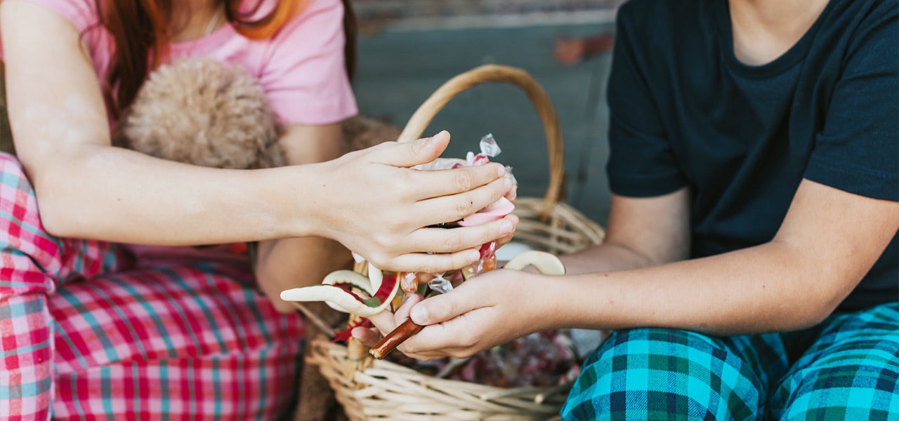 Two kids in pajamas sifting through a basket of candy