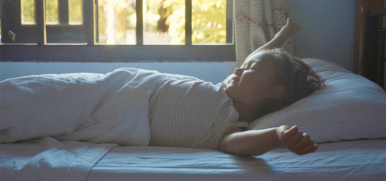 Small child stretching in bed in the early morning 