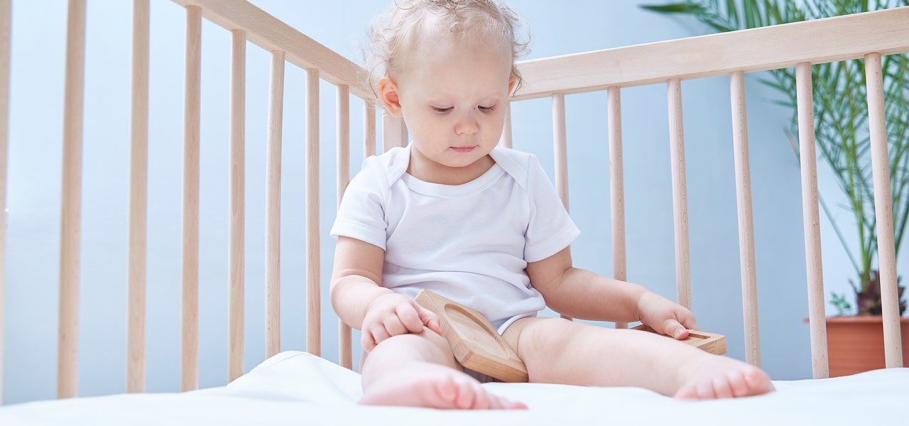 Toddler child sitting up and playing with a wooden toy