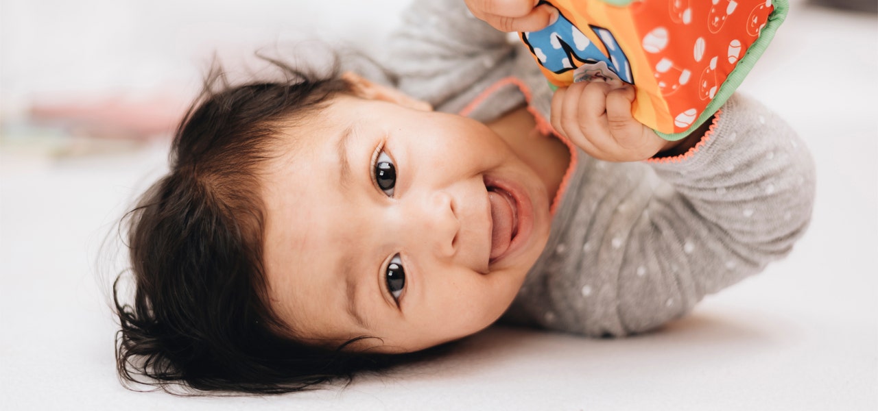 Happy toddler plating with brightly colored toy and smiling