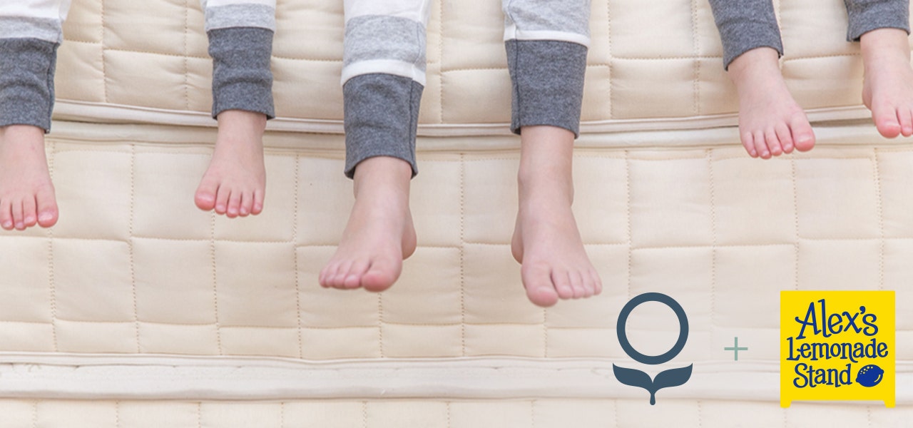 Three kids' feet dangling over the side of a Naturepedic organic mattress