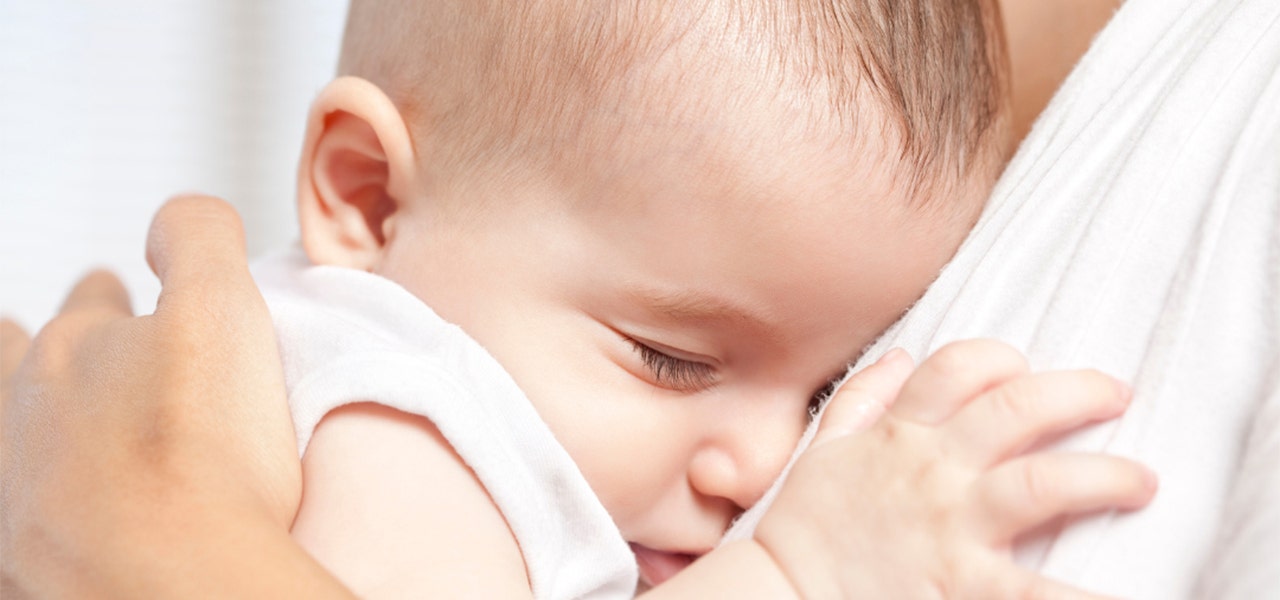 Overtired baby drifting off to sleep in a parent's arms