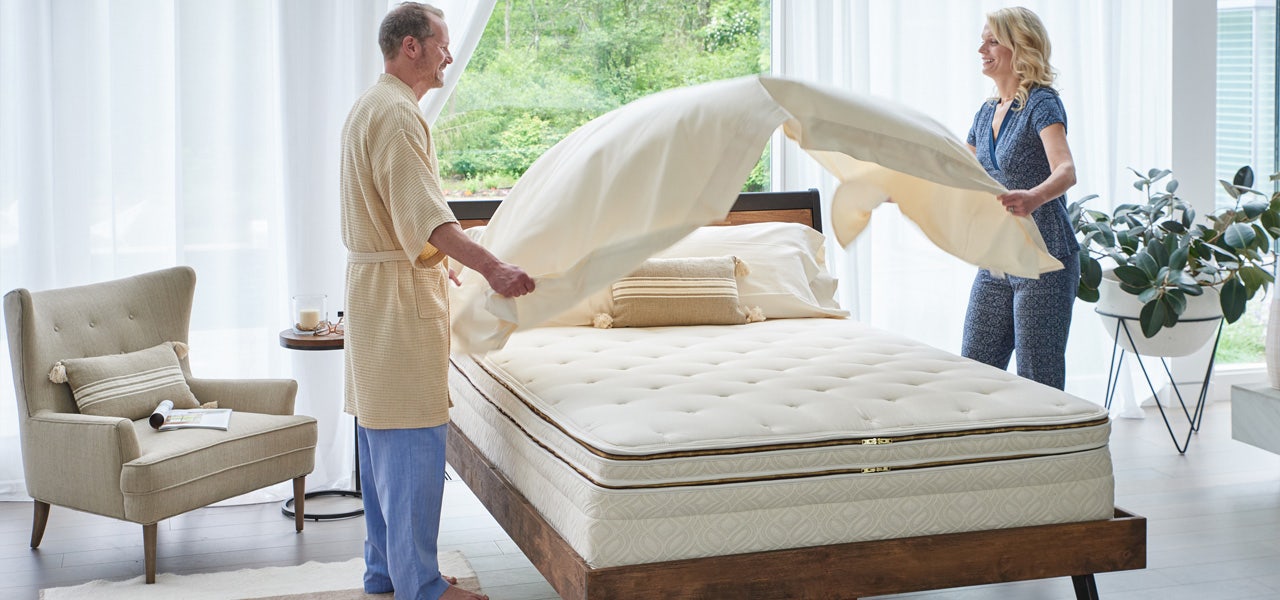 Man and woman changing the sheets on their bed