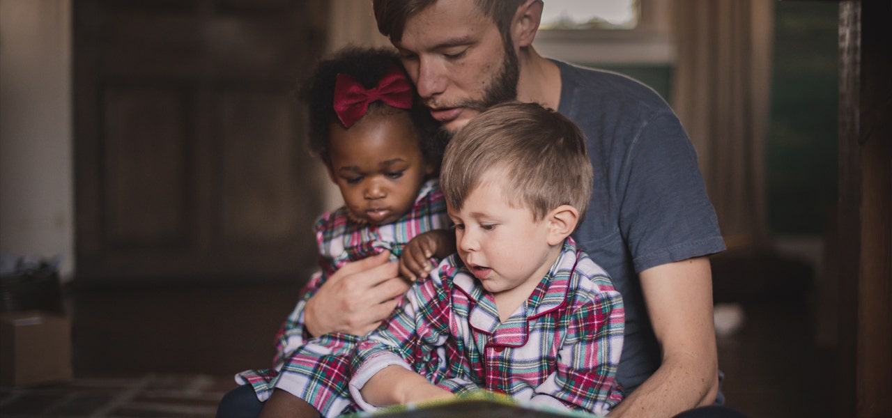 Father cuddling his kids and reading storybooks 