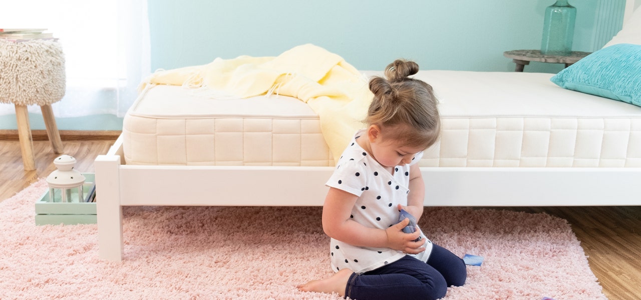 Young girl playing on ther floor next to her bed