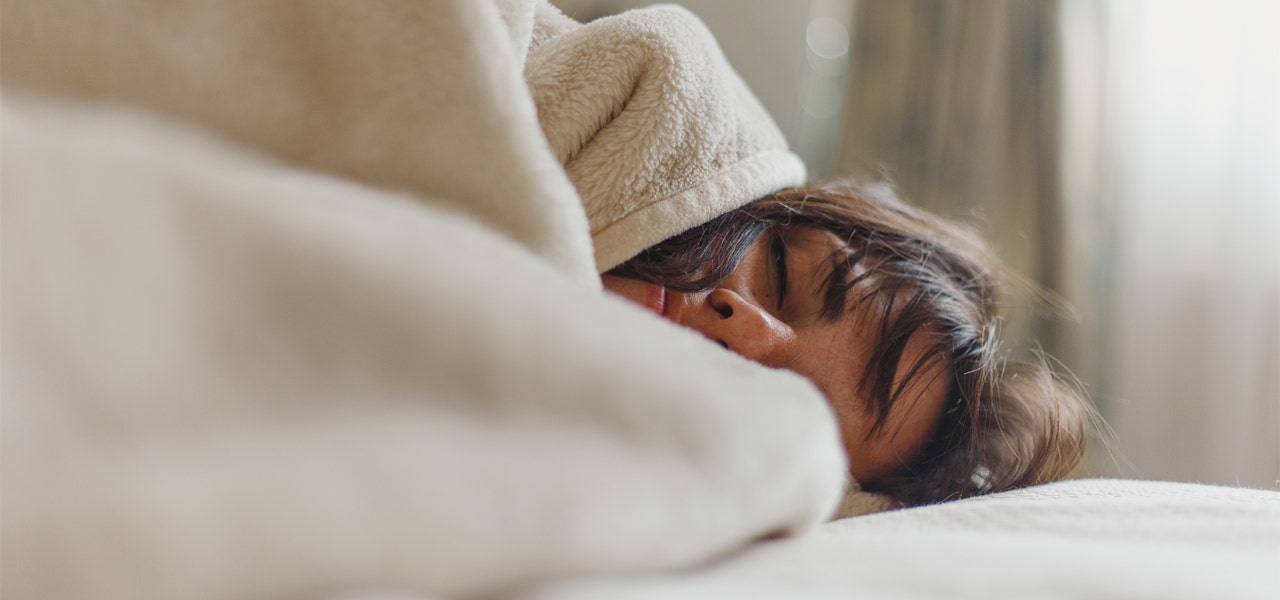 Woman sleeping soundly under a white fleece blanket