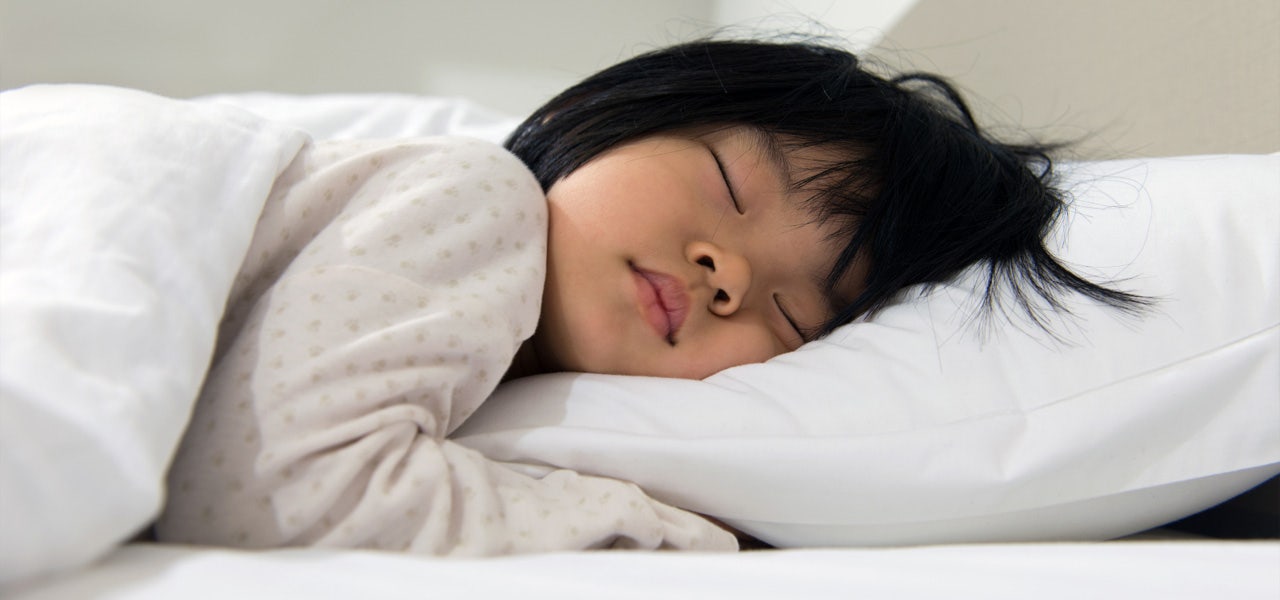 Small child sleeping in bed, where conventional mattresses make kids vulnerable to toxic chemicals