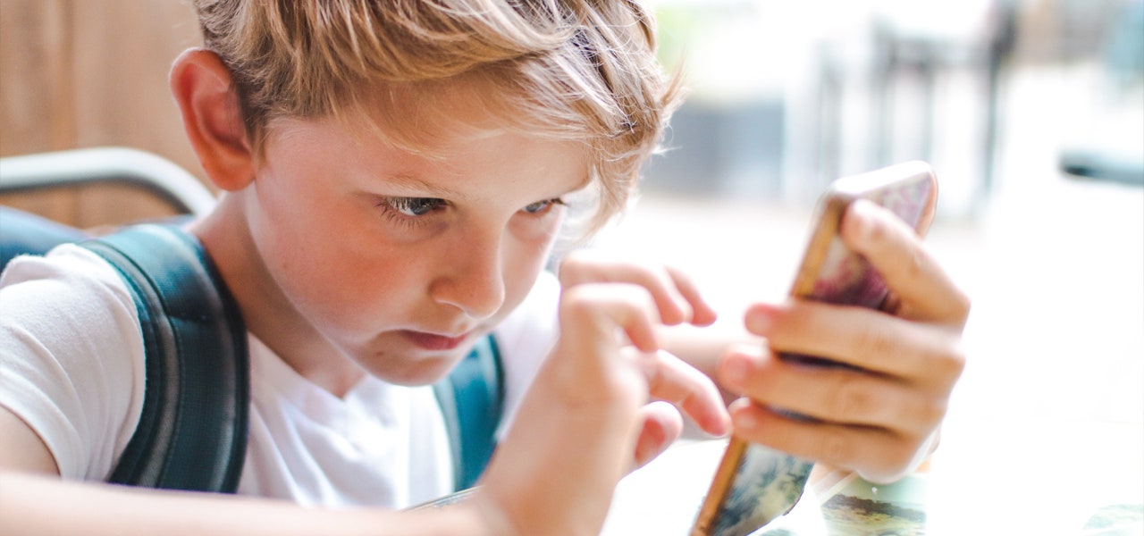 Middge grade boy wearing a backpack and looking at his phone