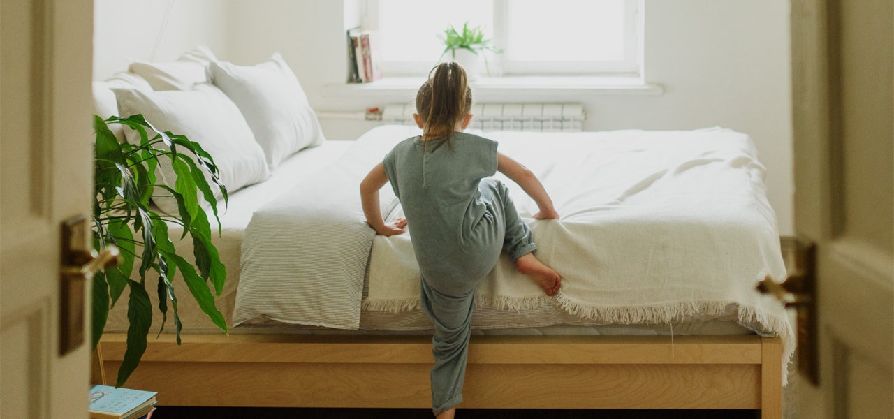 Young girl climbing into her comfortable bed