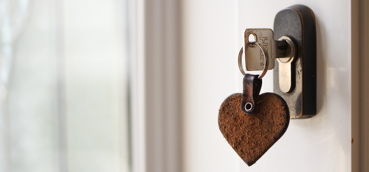 Keys in a locked front door wirth heart-shaped keychain