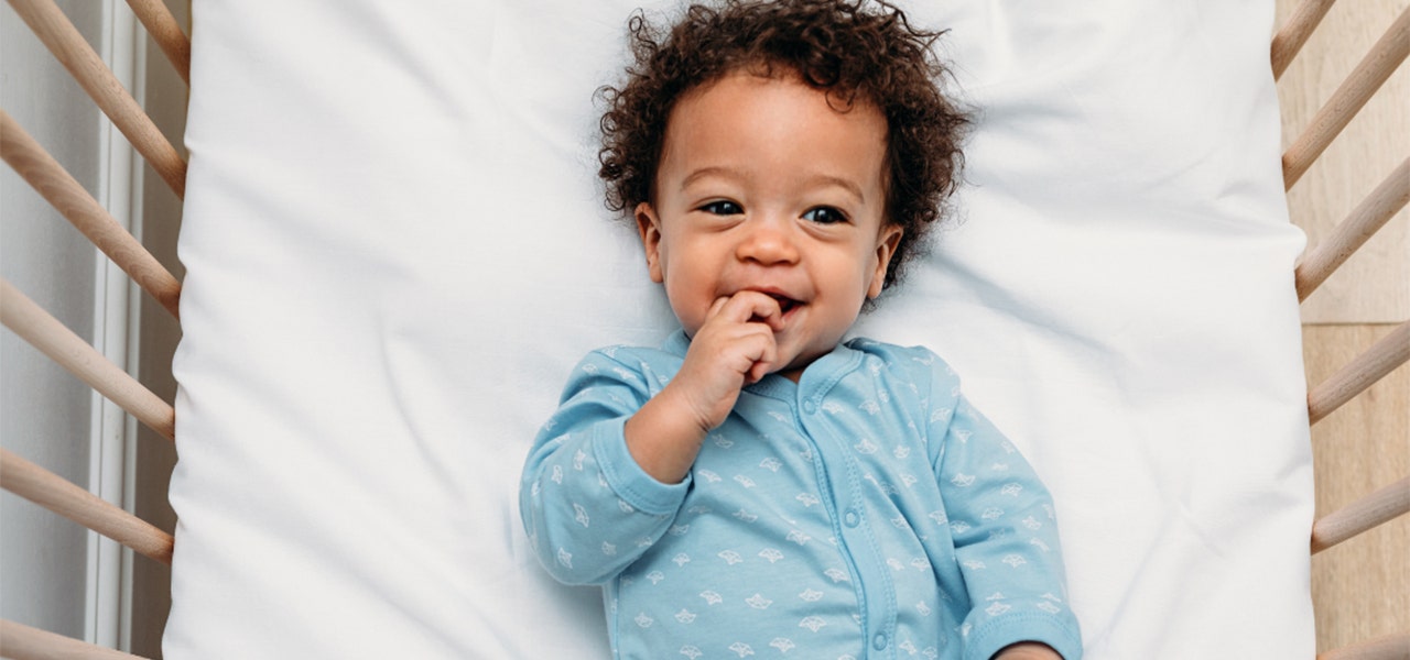 Smiling, healthy baby lying wide awake in the crib