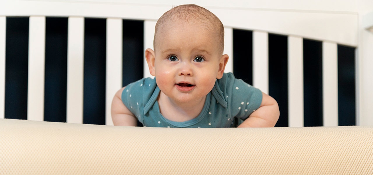 Wide awake baby enjoying tummy time on a Naturepedic organic mattress