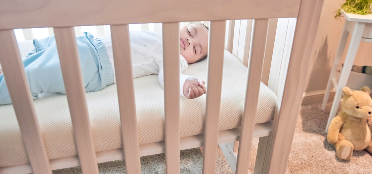 Baby sleeping safely on their back in on a firm mattress with a safe, snug fit