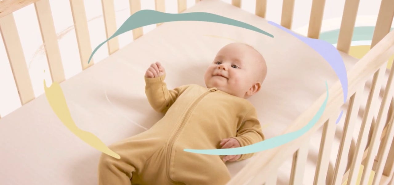 Baby lying on organic breathable mattress with illustrated airflow lines swirling around