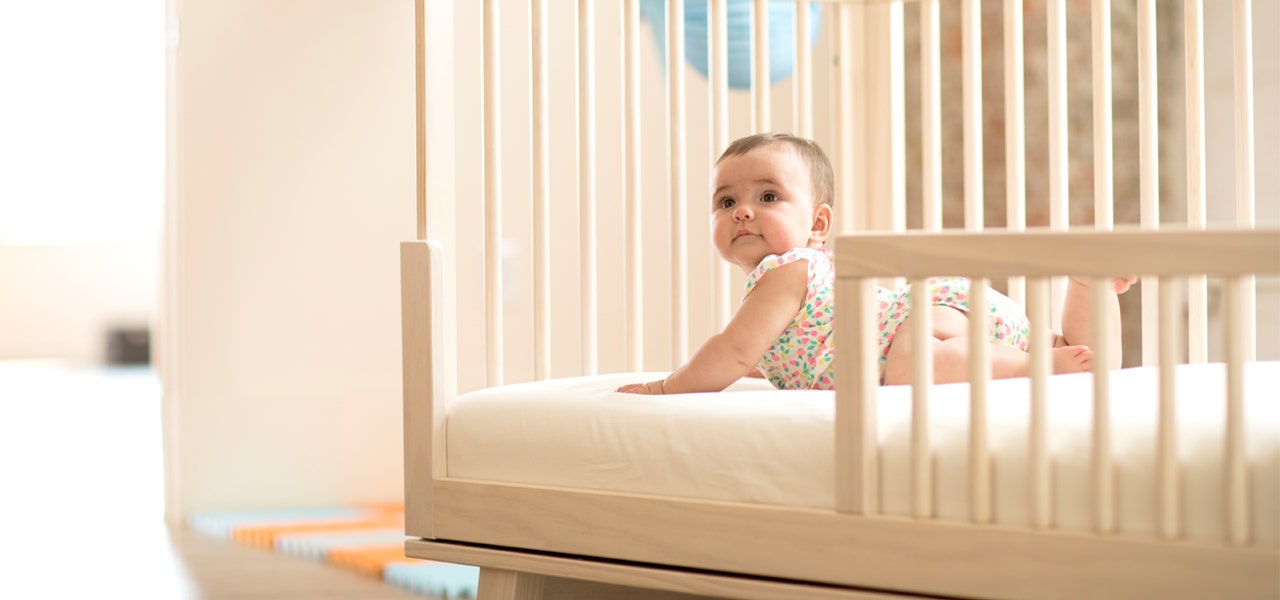 Baby girl enjoying safe tummy time on her organic crib mattress