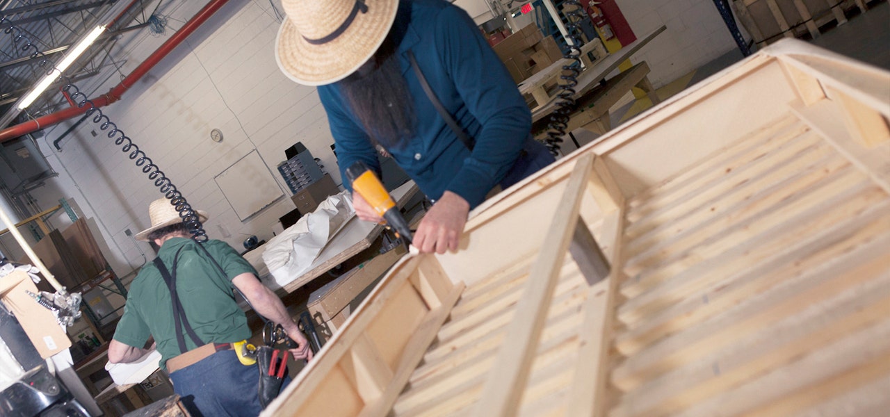 Amish craftman in Naturepedic factory using tools on a pine foundation