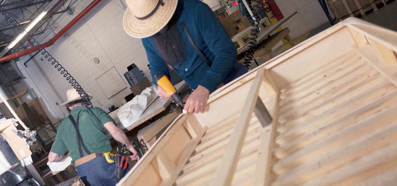 Amish craftman in Naturepedic factory using tools on a pine foundation 