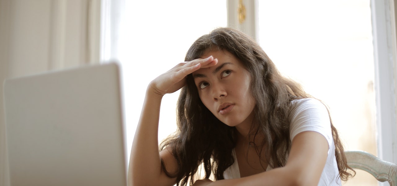 Young woman working at a laptop but suffering from seasonal fatigue