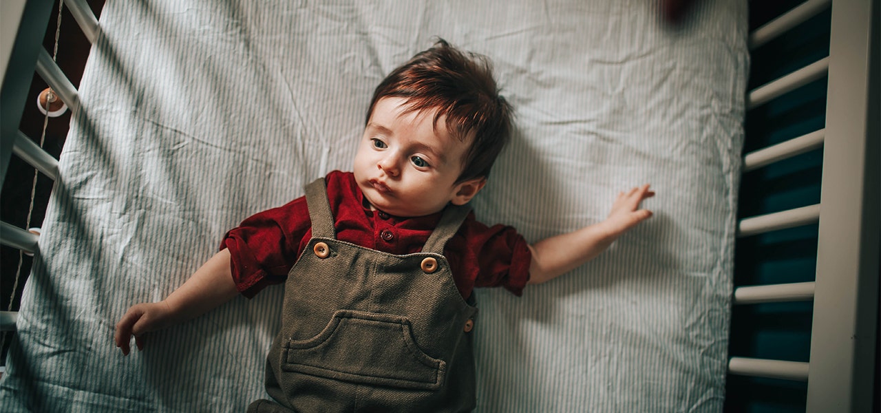 Baby lying awake on a 2-stage organic crib mattress