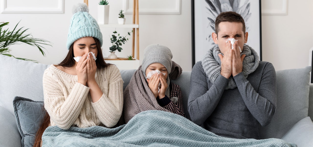 Mom, dad and child all suffering from flu symptoms together on the couch