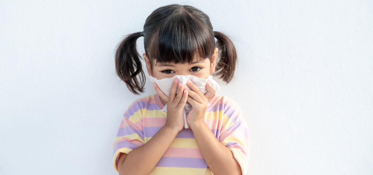 Young girl blowing her nose