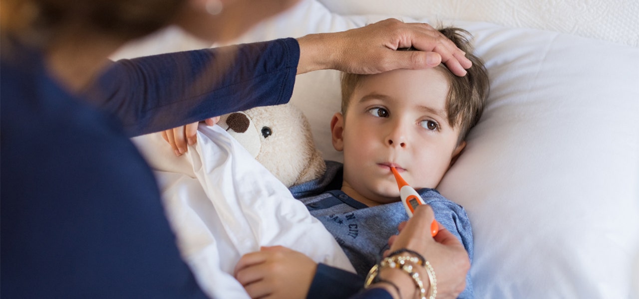 Mother taking her sick child's temperature in bed