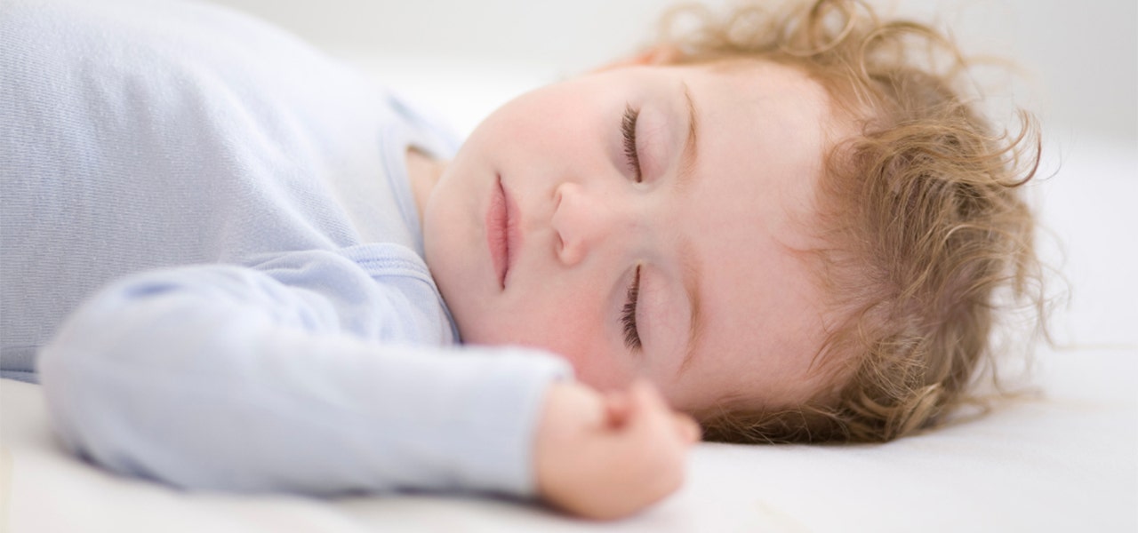 Baby sleeping peacefully on a safe sleep surface