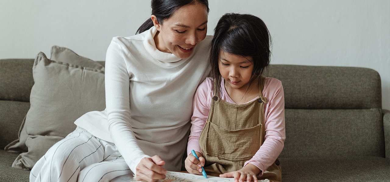 Mother and daughter coloring together on the couch