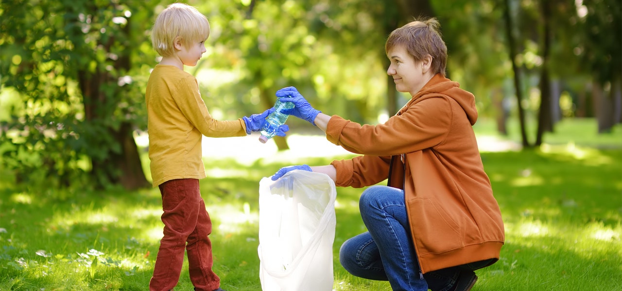 Mother and son picking up plastic bottles together in the park