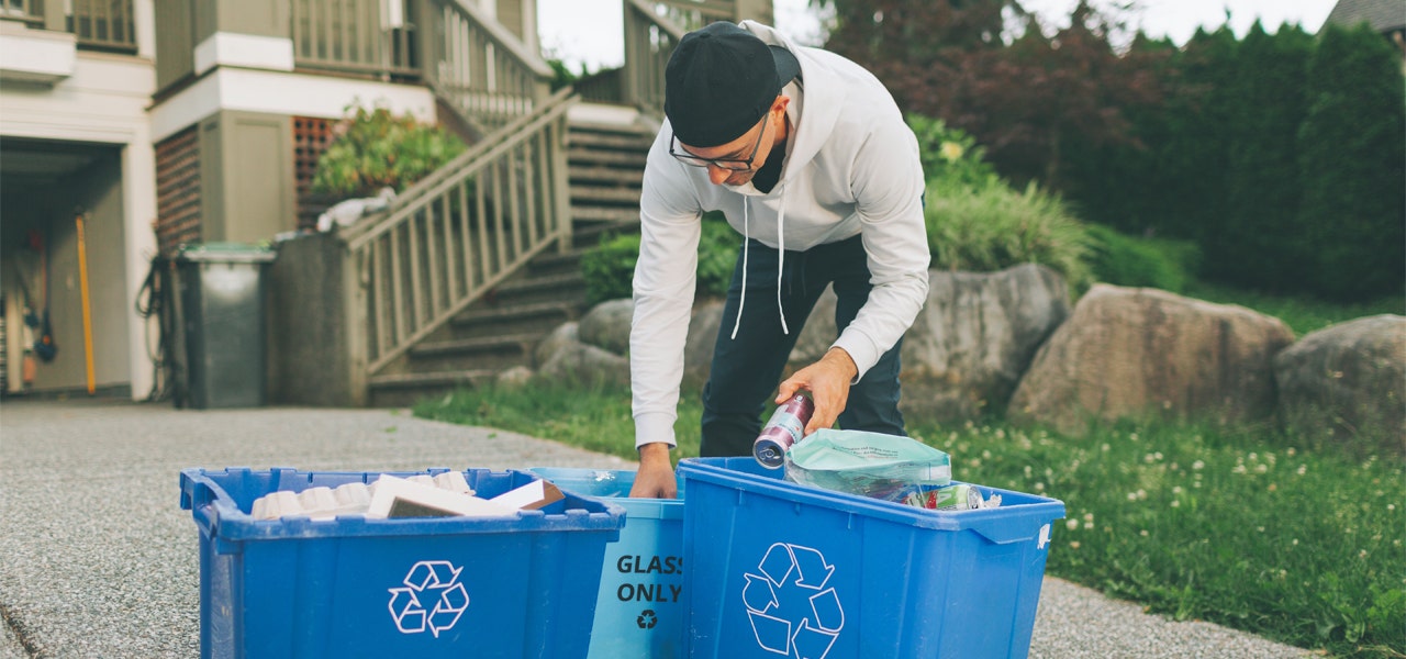 Man sorting through recycling bins at the curb