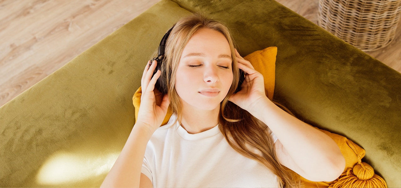 Woman listening to a guided meditation with headphones on and eyes closed