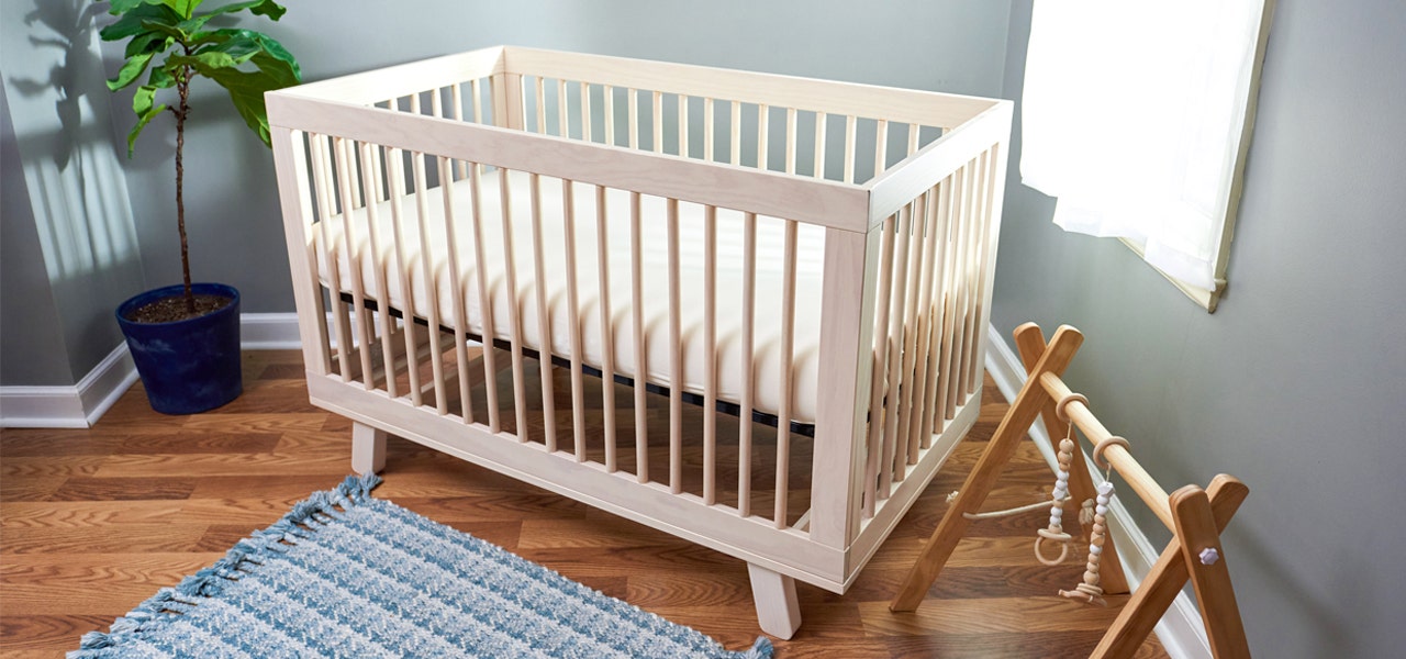 Unfinished wooden crib in a cozy nursery