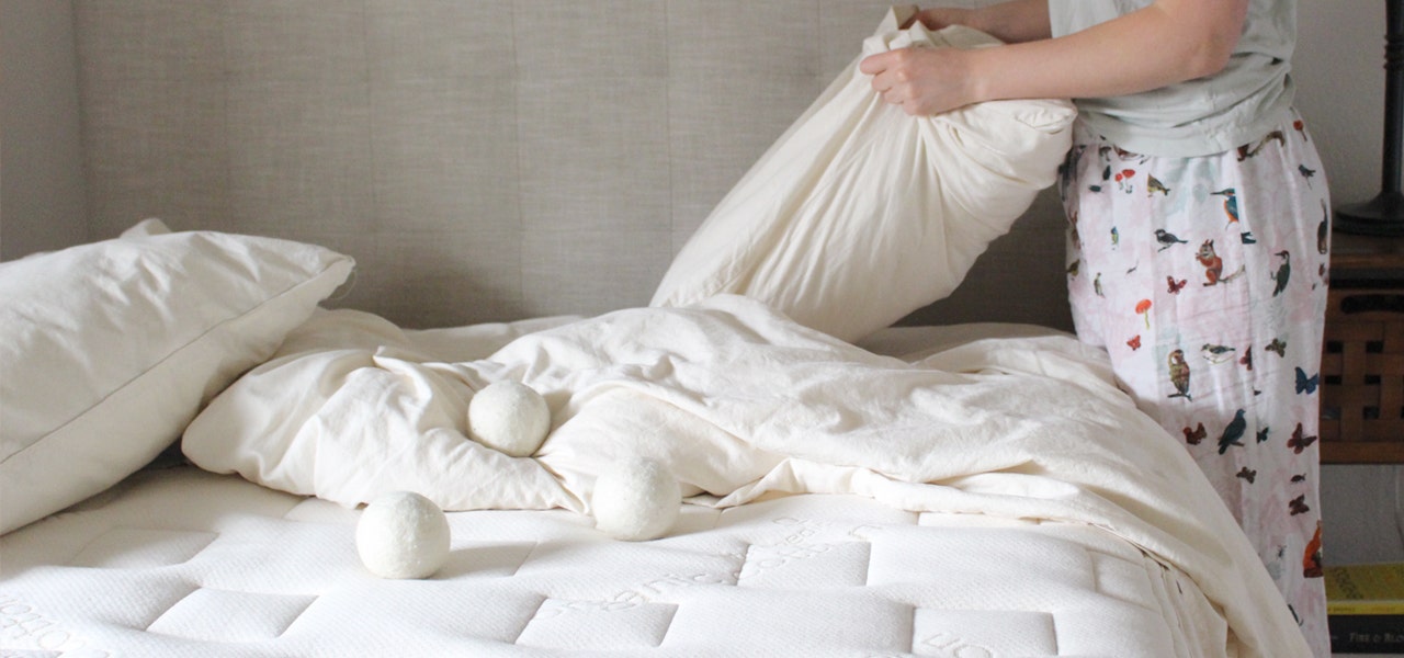 Person in pajamas changing the bedding on their organic mattress