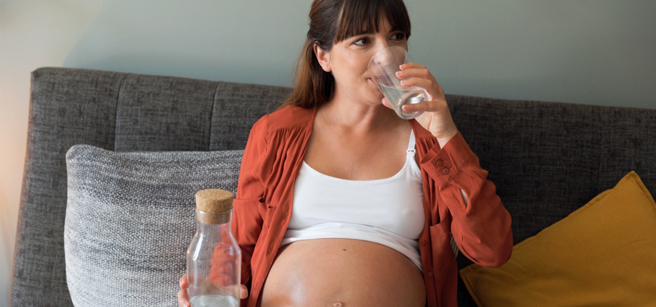 Pregnant woman drinking a tall glass of water