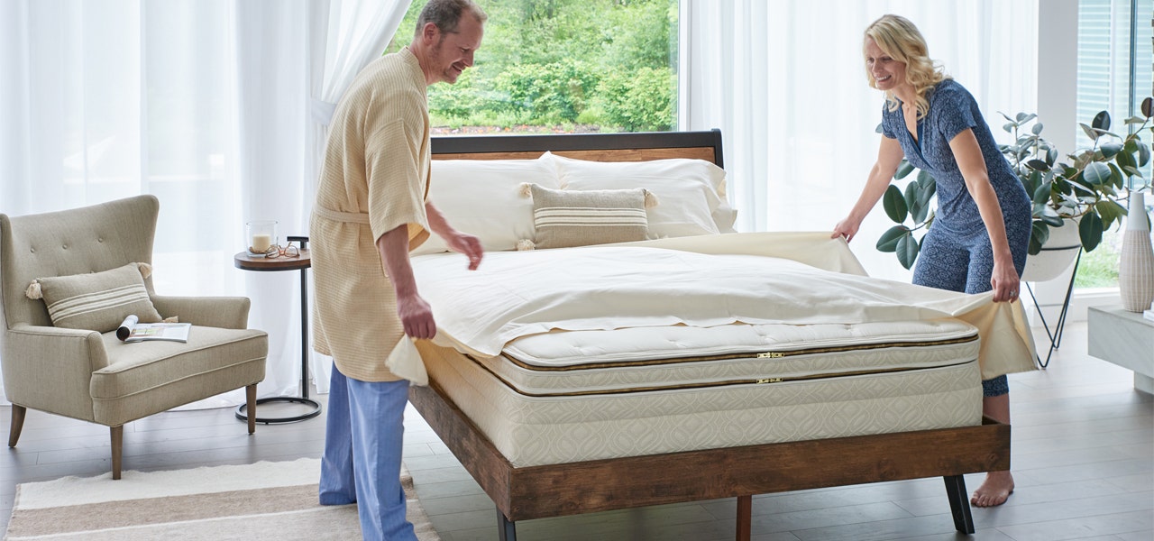 Couple putting fresh bedding on a clean organic mattress