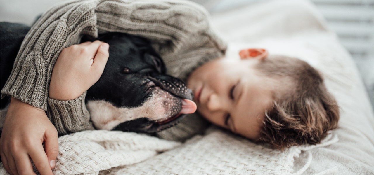 Child cuddling a black dog