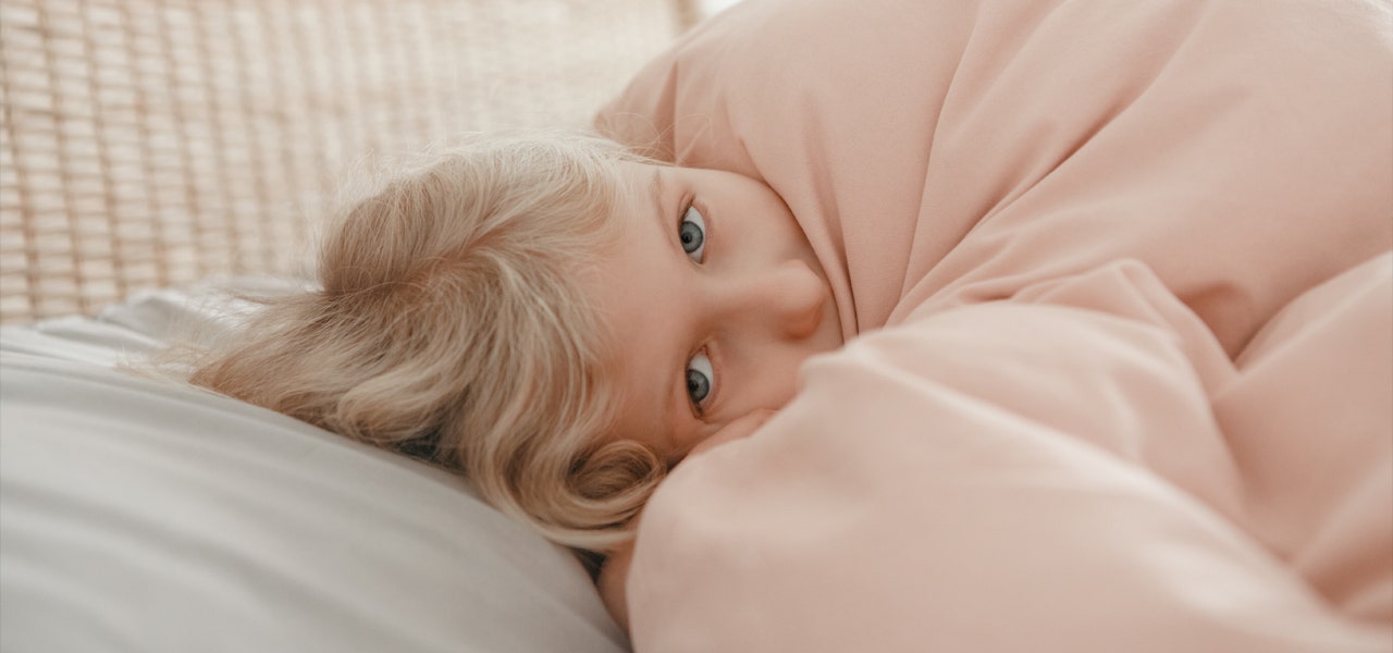 Small girl snuggled under her blankets but still awake