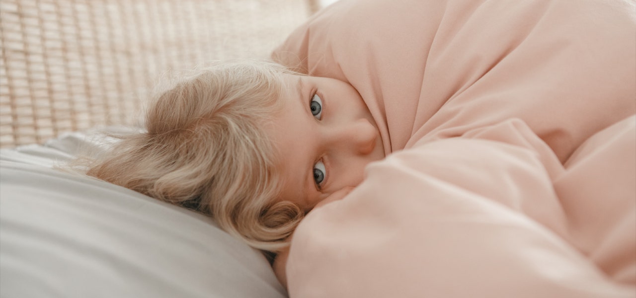 Small girl snuggled under her blankets but still awake 