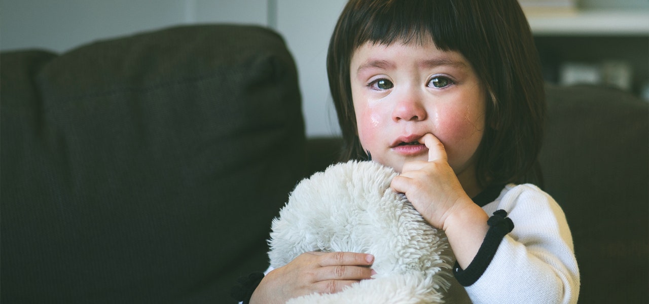 Young girl cuddling a soft toy and crying