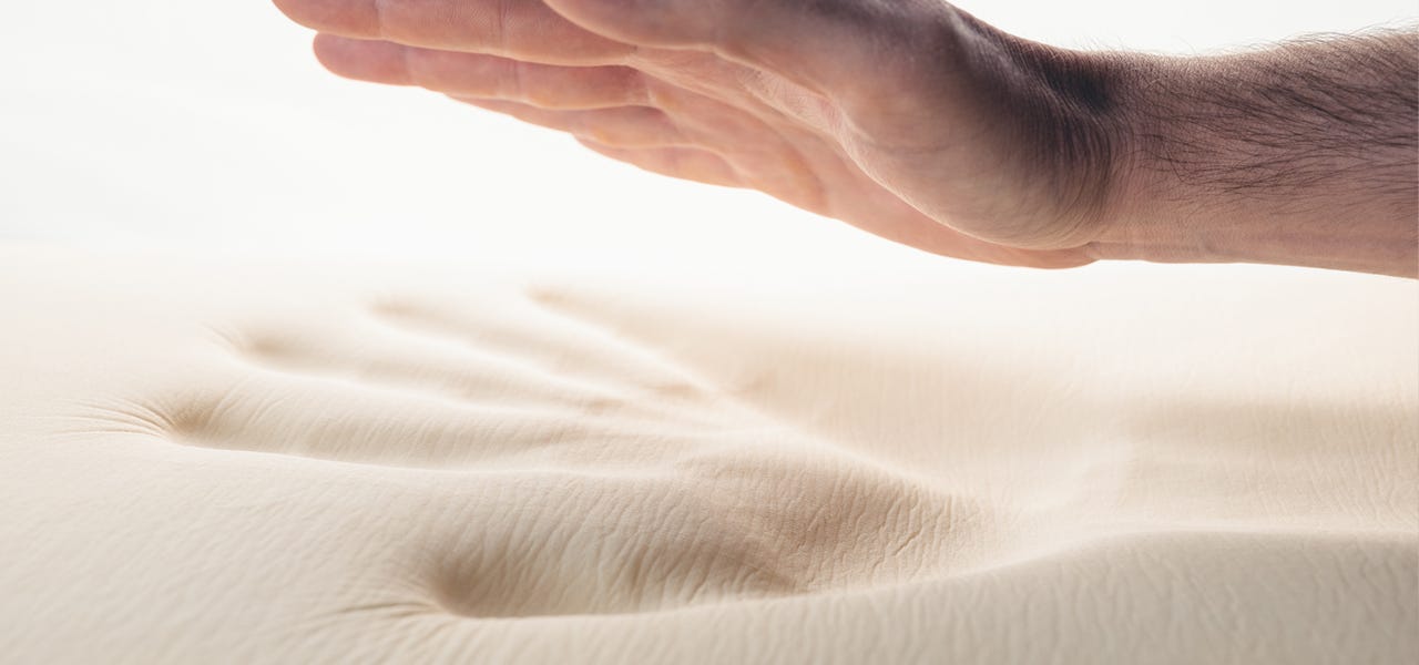 Hand leaving an imprint on a memory foam mattress