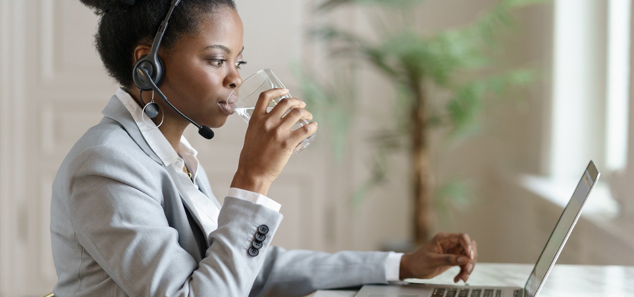 Young professional woman drinking water to stay hydrated at work