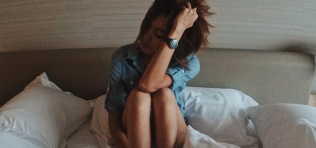 Very groggy woman sitting up in bed