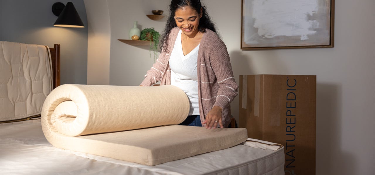 Smiling woman unrolling the comfort layers of of EOS organic mattress