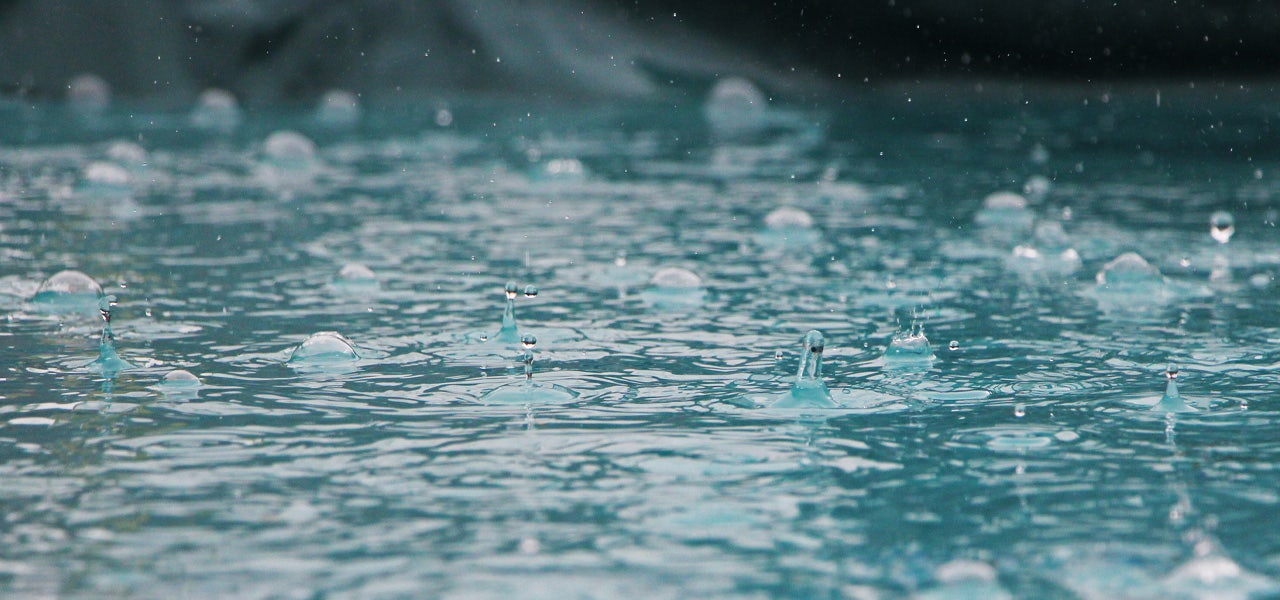 Close up of raindrops splashing into a puddle