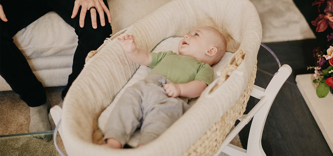 Baby lying in bassinet and smiling up at their parent