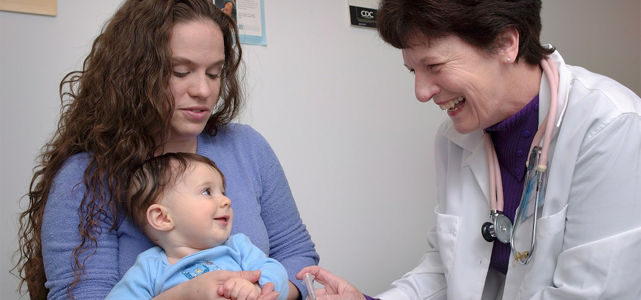 Peditrican examining a toddler during their annual check-up