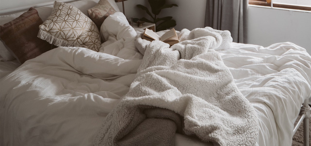 Organic blankets and sheets on an unmade bed